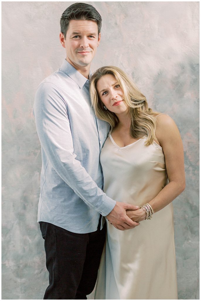 Pregnant Mother Rests Her Head On Her Husbands Shoulder During Their Studio Maternity Session