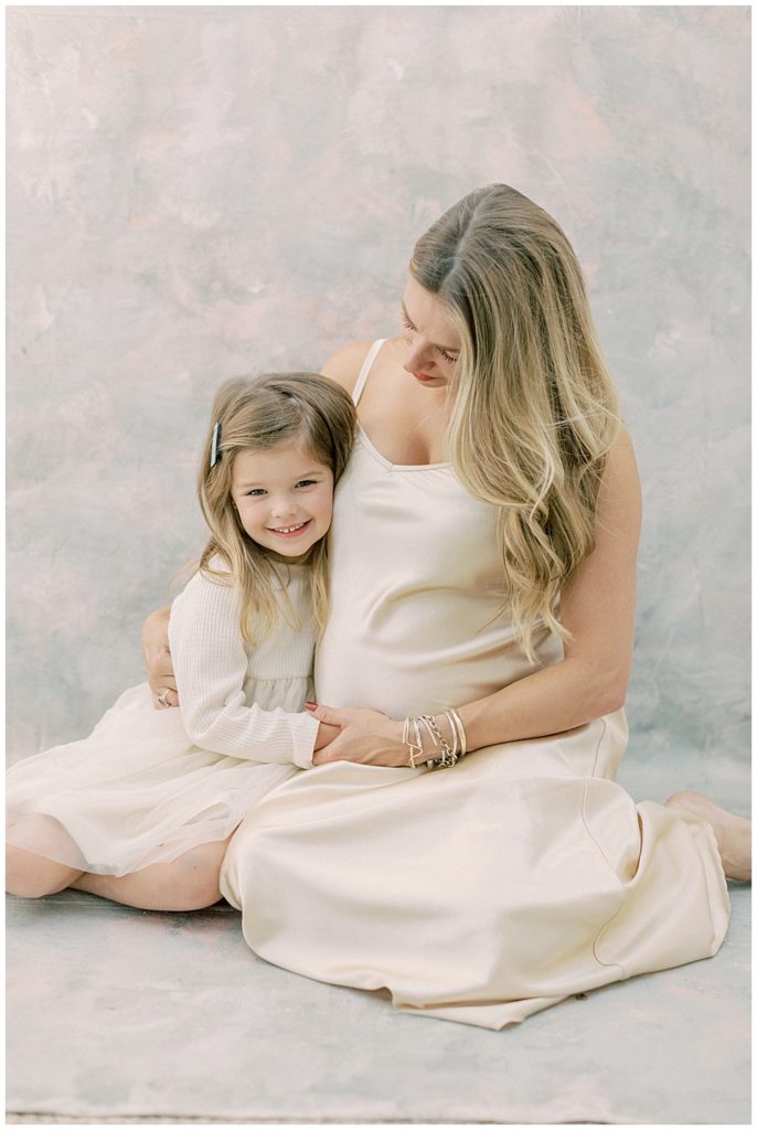 Mother Sits With Her Little Girl During Their Studio Maternity Session Outside Of Northern Va