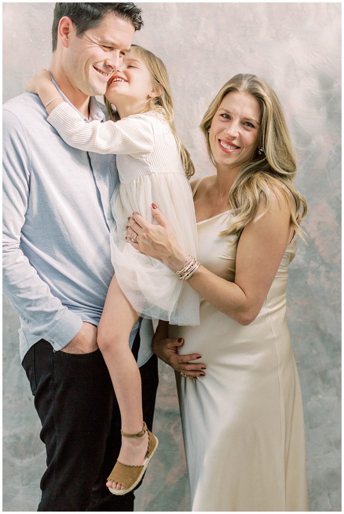 Parents Embrace Their Little Girl During Their Maternity Session In A Studio