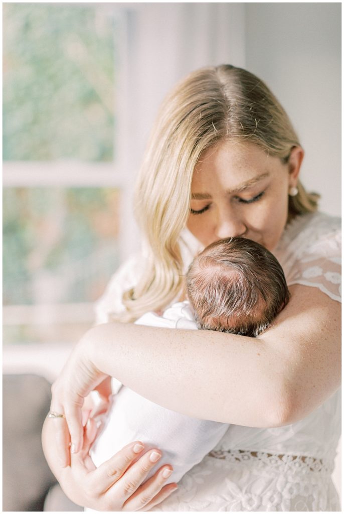 A Mother Brings Her Newborn Up To Her Face For A Kiss During Their Arlington Newborn Session