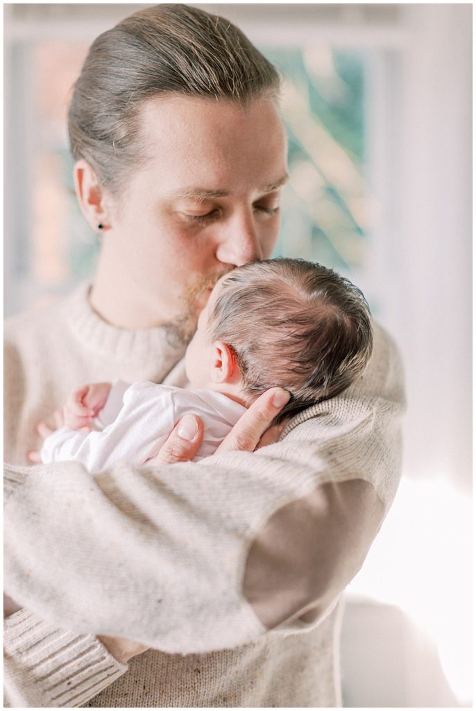 Dad Brings His Baby's Head Up To His And Kisses Her Forehead During Their Arlington Newborn Session