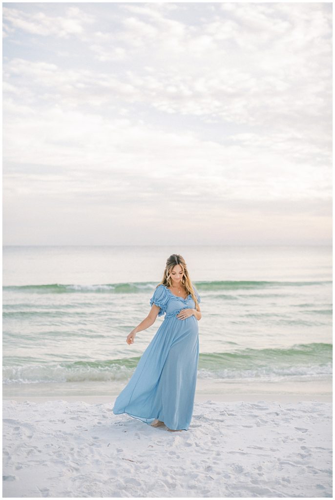 Pregnant Mother In Blue Dress Lets Her Dress Blow In The Wind During Her Beach Maternity Session