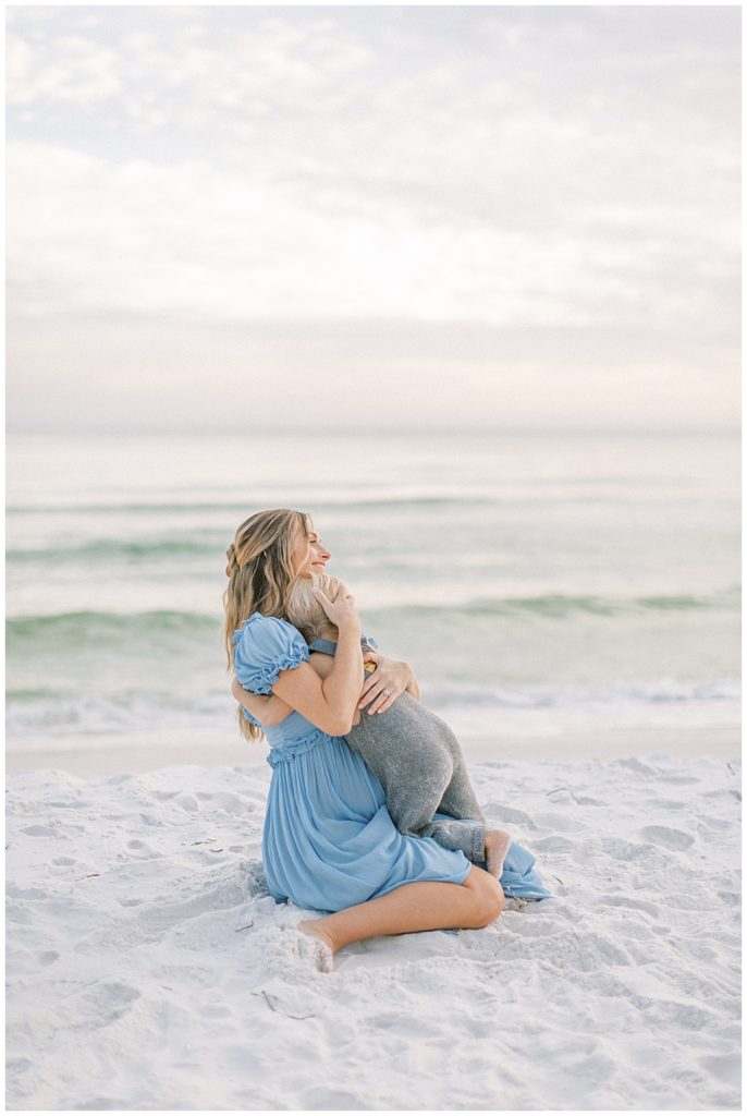 Young Boy Gives His Mother A Hug While Sitting On The Beach