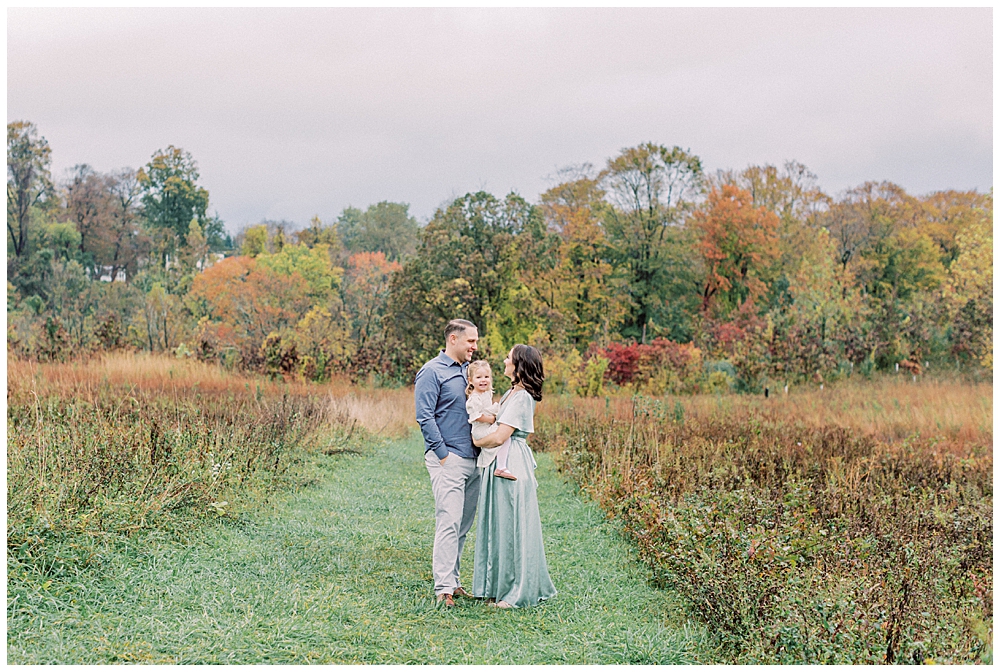 Parents Look At One Another While Holding Their Toddler Daughter During Their Howard County Conservancy Photo Session