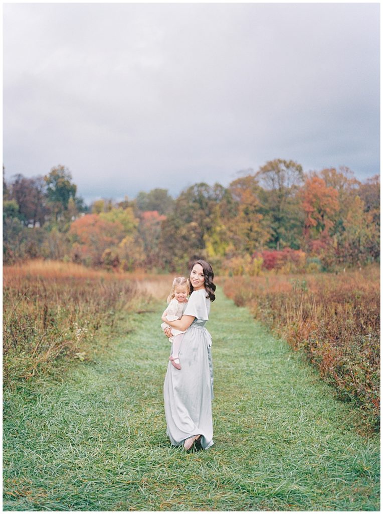 Mother Walks Holding Her Toddler Daughter In The Howard County Conservancy During Their Fall Session And Turns To Look Back At The Camera