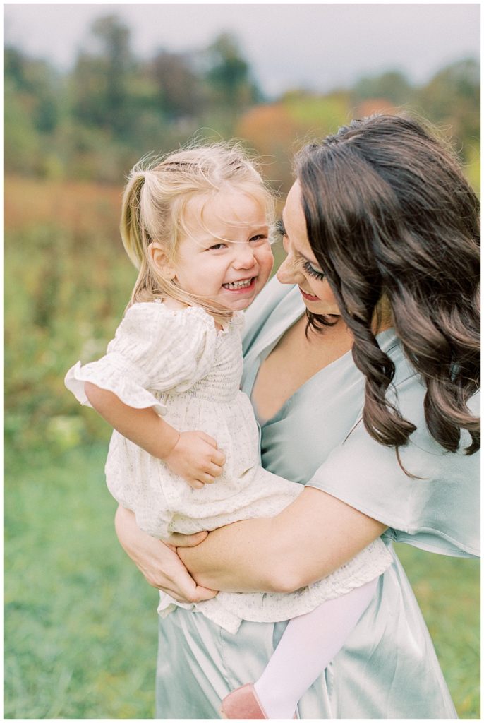 Mother And Toddler Daughter Smile Together While Mother Holds Her