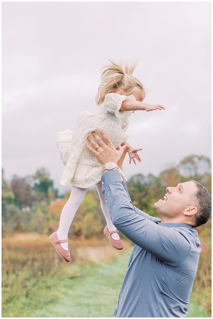 Father Throws His Daughter Up In The Air During Their Family Photo Session At The Howard County Conservancy