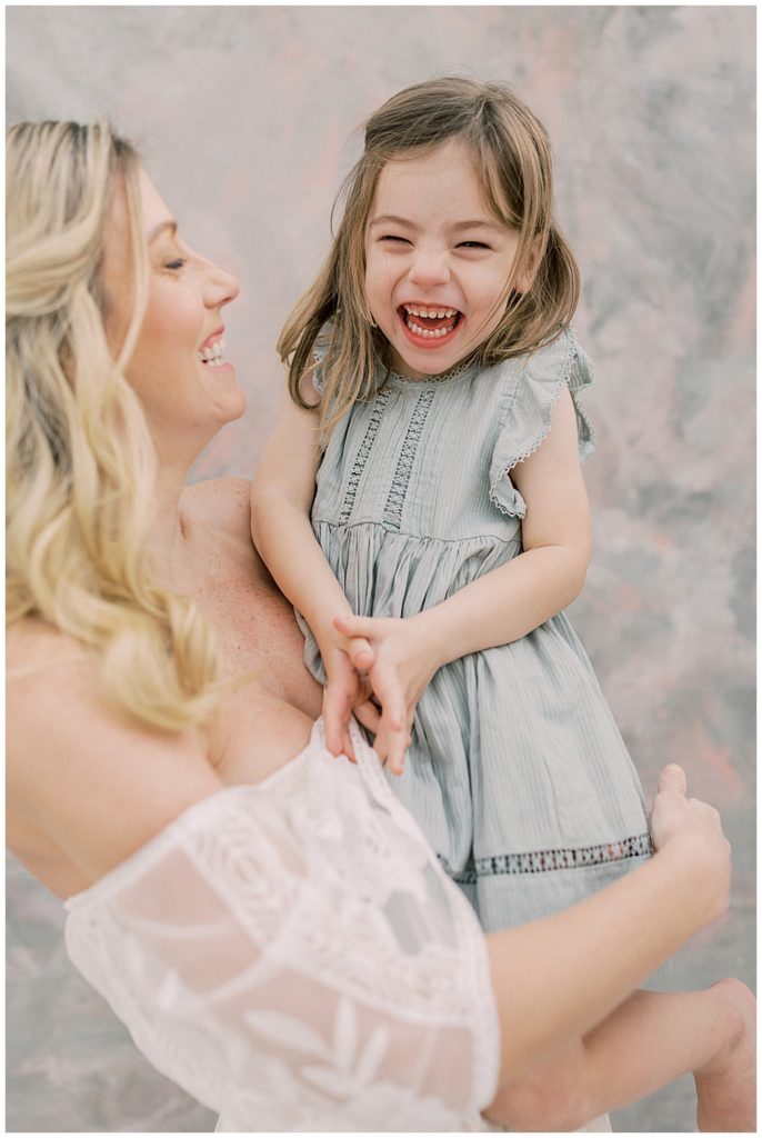 A Mother Holds Her Little Girl While They Both Laugh 