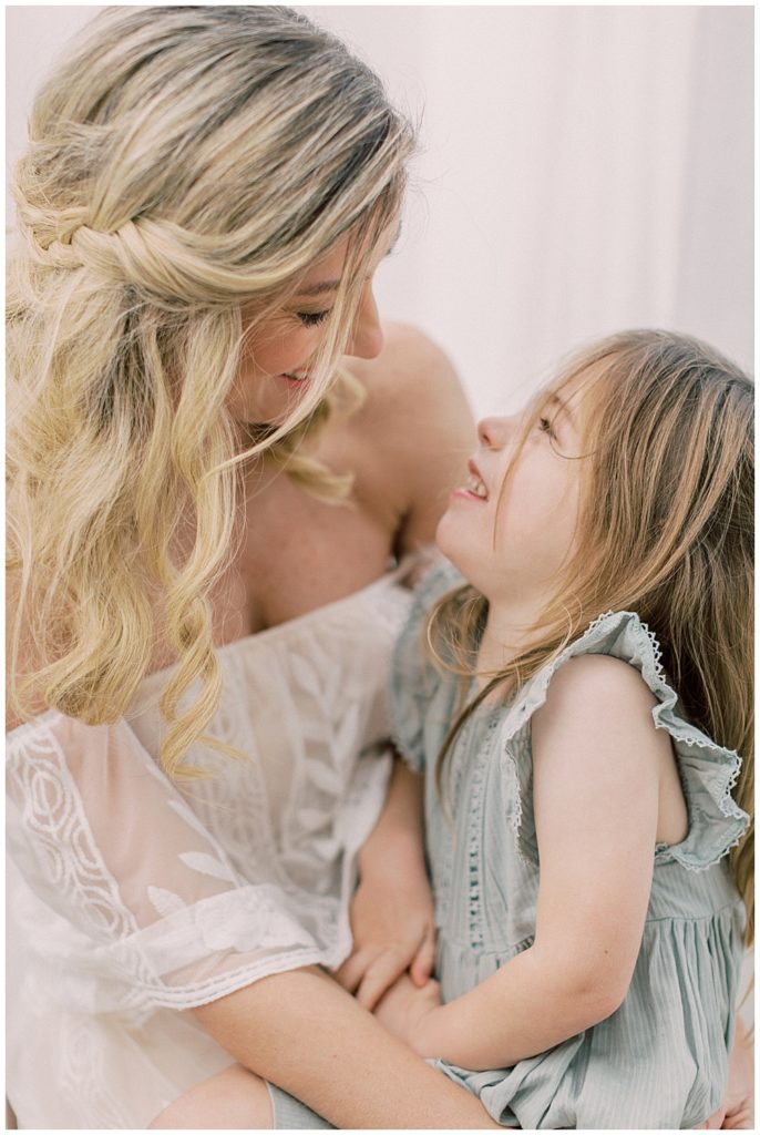 A Mother And Daughter Look At One Another And Laugh During Their Studio Motherhood Session In Bethesda Maryland