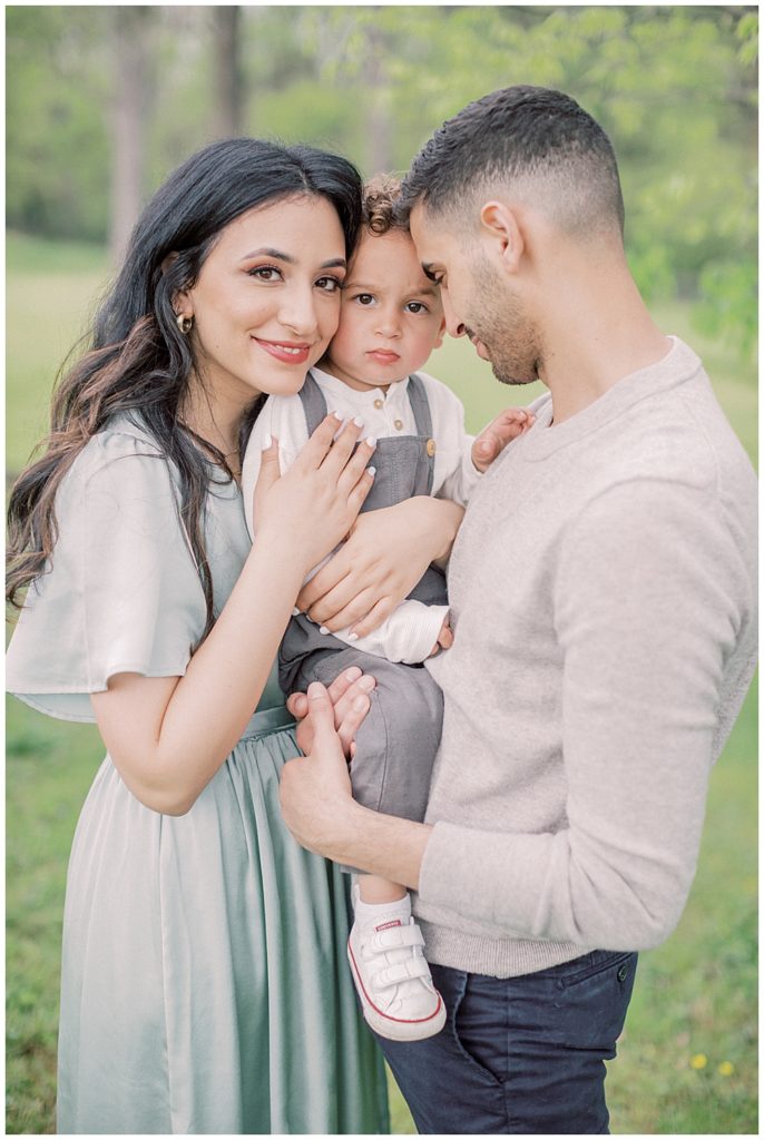 Mother And Father Stand And Hold Their Toddler Son Close To Them