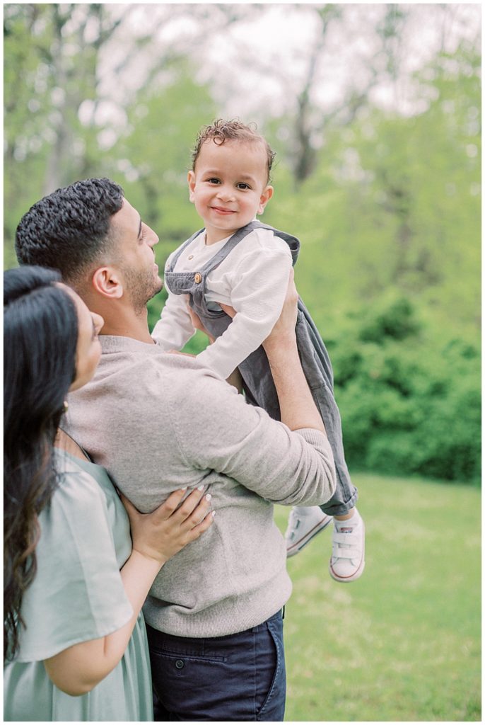 Mother And Father Hold Up Their Little Boy While He Smiles