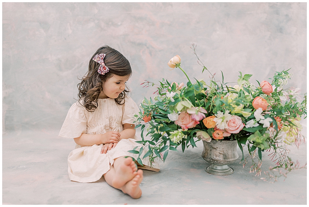 A Little Girl Sits And Looks Next To A Floral Display In A Photography Studio In Washington Dc