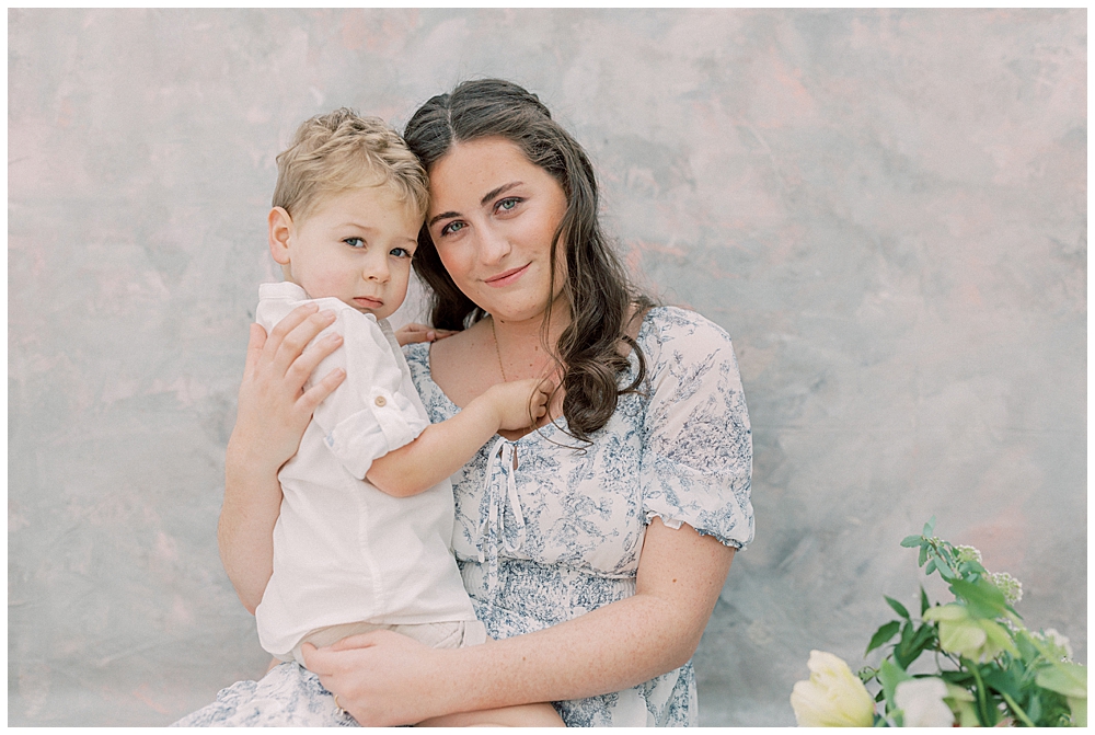 A Mother Holds Her Son Up To Her A Looks At The Camera During Her Studio Motherhood Session