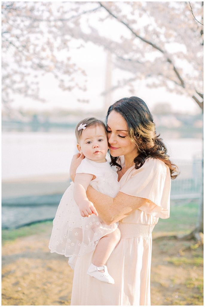 A Mother Snuggles Up To Her Daughter By Cherry Blossom Trees In Washington Dc