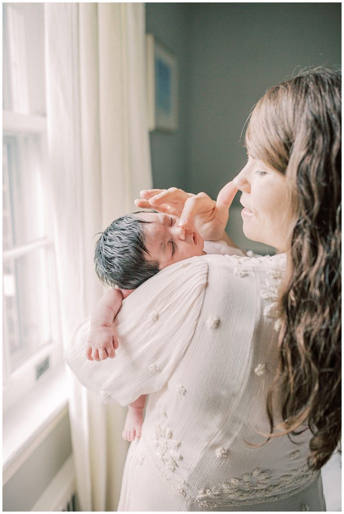 A Mother Takes Her Finger And Traces The Nose Of Her Newborn Daughter