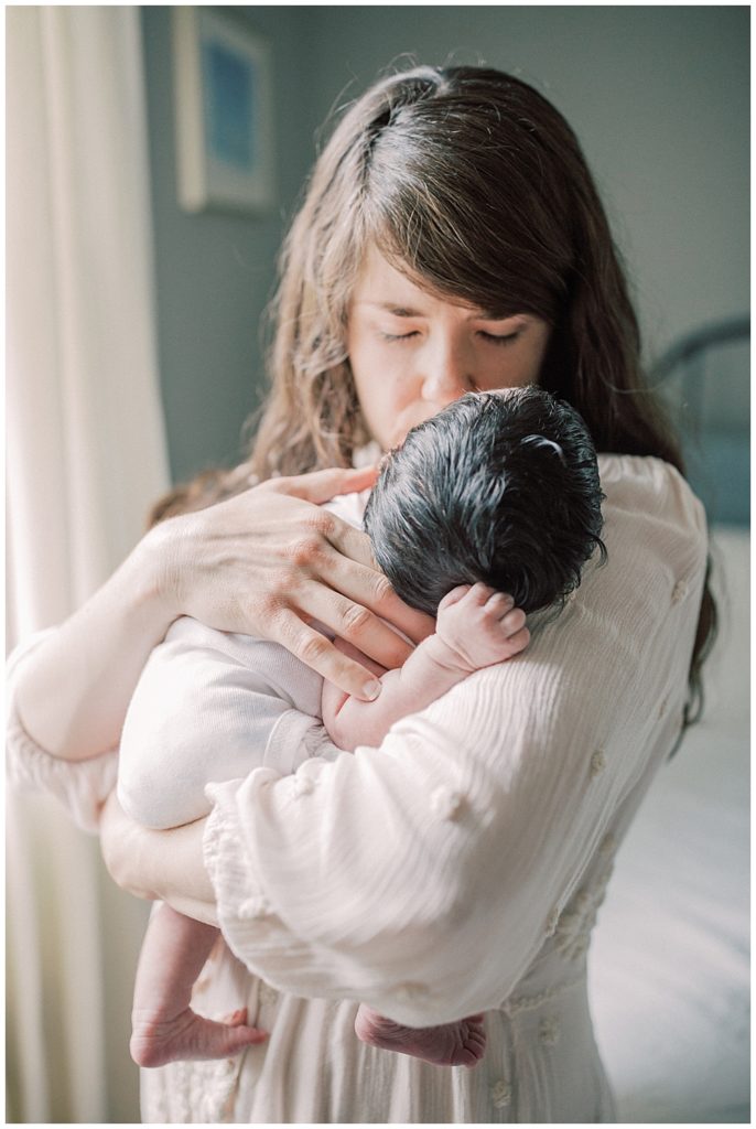 A Mother Holds Her Newborn Daughter Up To Her And Kisses Her Head.