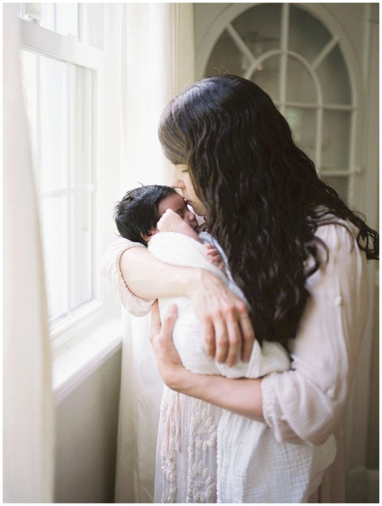 A Mother Kisses Her Baby Girl On The Head.