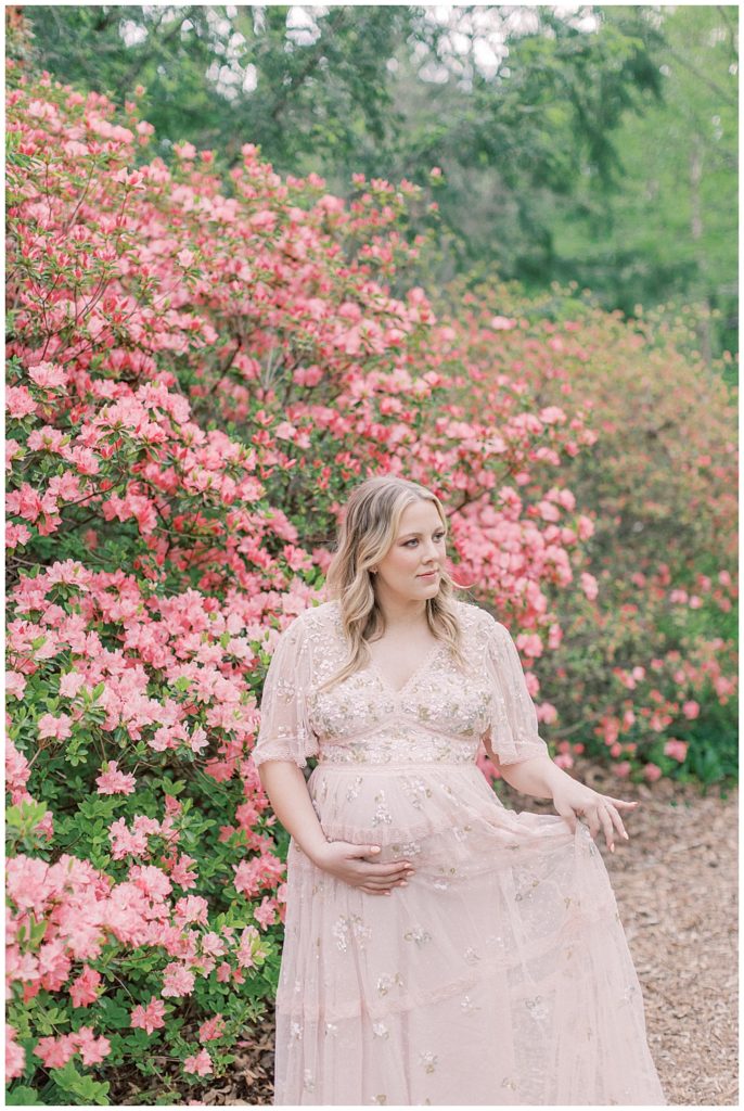 A Blonde Pregnant Woman In A Pink Needle &Amp; Thread Dress Stands Near A Pink Azalea Bush In Brookside Gardens During Her Maternity Session