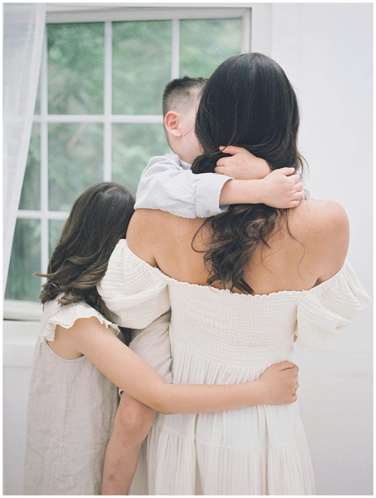 A Mother Holds Her Son While Her Daughter Looks At Her