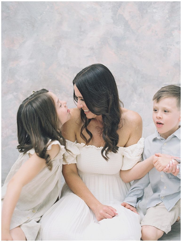 A Mother Sits With Her Son And Daughter During Her Mama And Me Session With Two Kids And Smiles