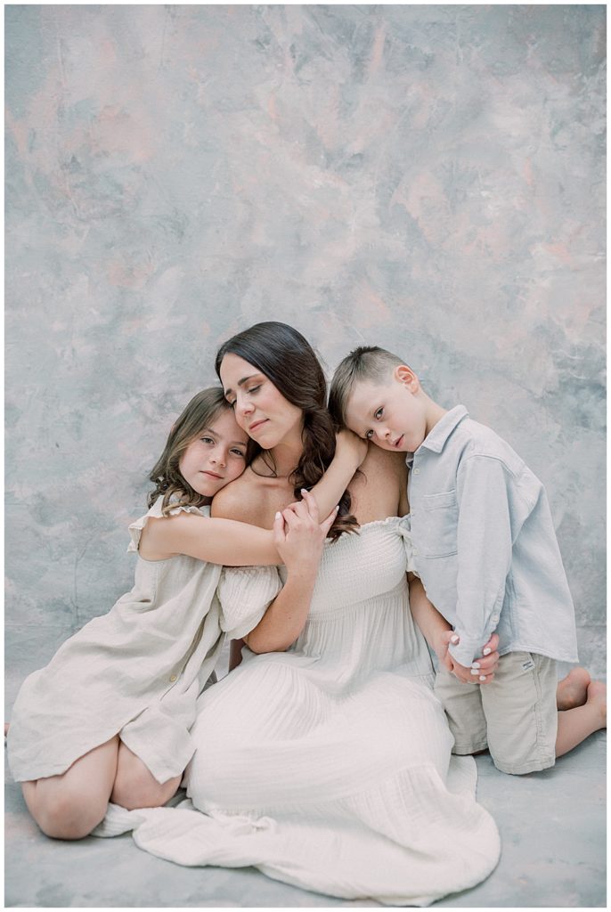 A Mother Sits While Her Daughter And Son Cuddle In Close To Her