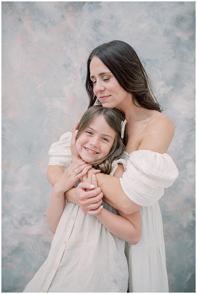 A Mother Stands Behind Her Daughter, Holding Her Close To Her