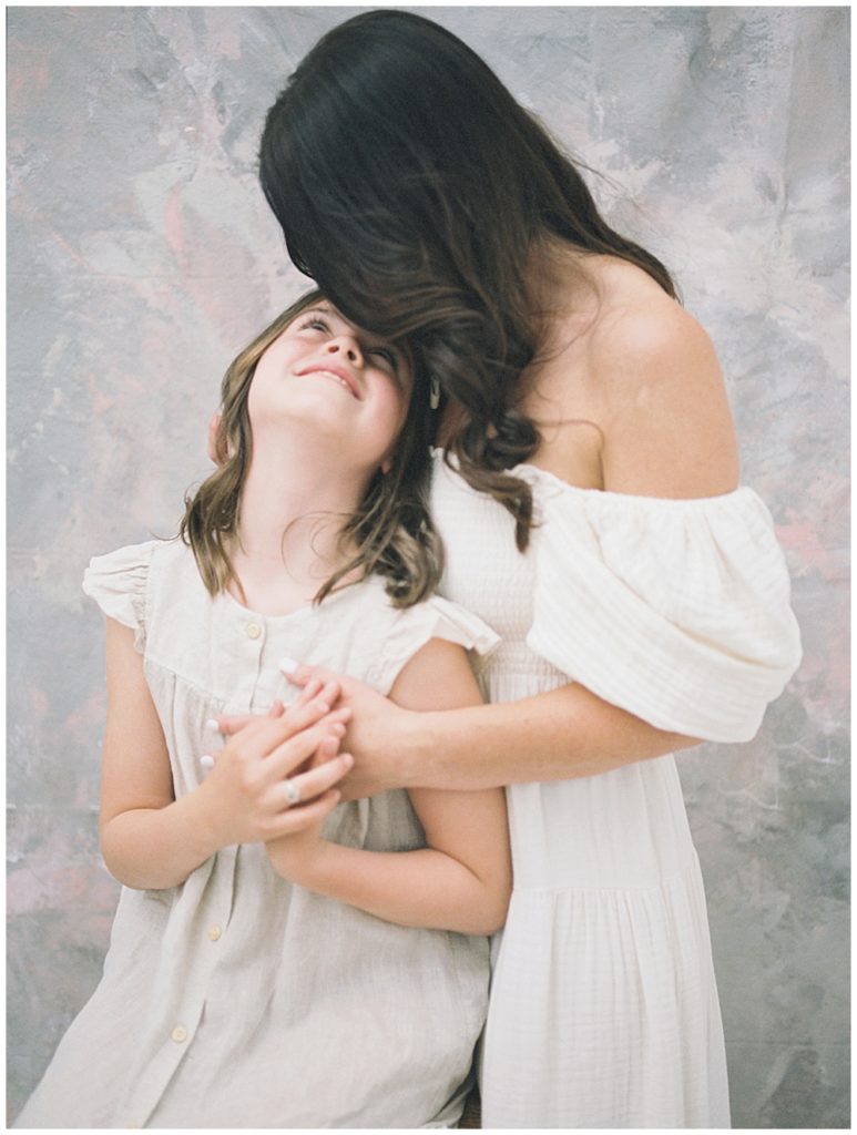 A Mother Kisses The Top Of Her Daughter's Head.