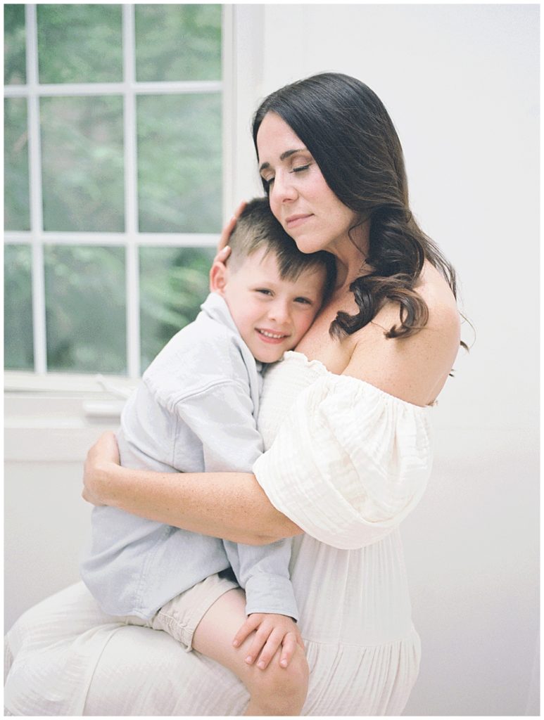 A Mother Sits With Her Son On Her Lap, Closing Her Eyes