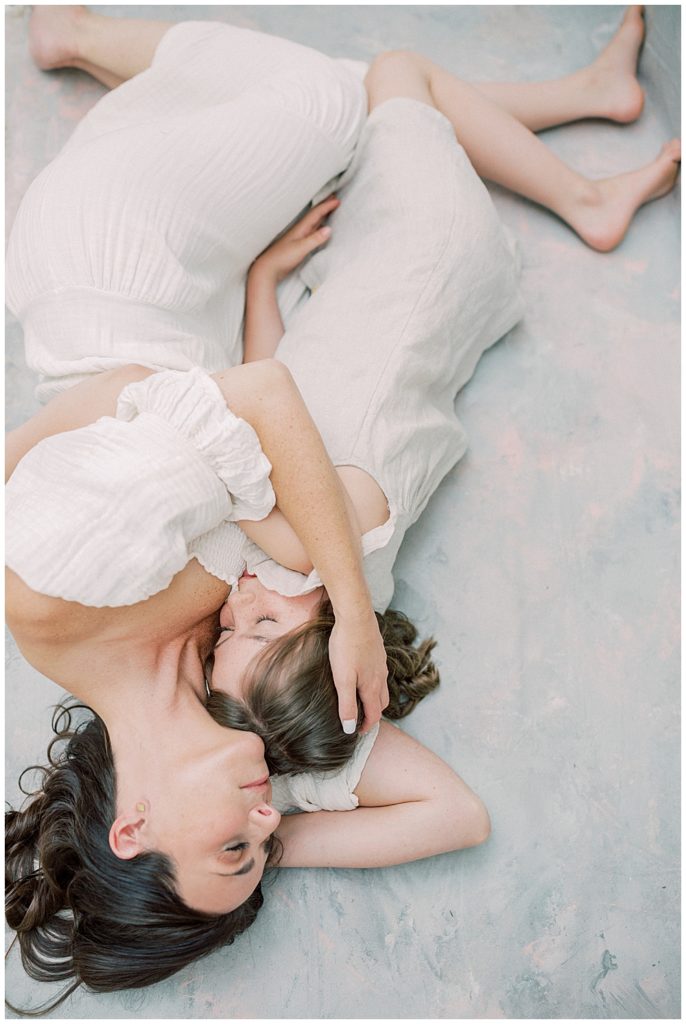 A Mother Lays Down And Holds Her Young Daughter Up To Her During Her Studio Session