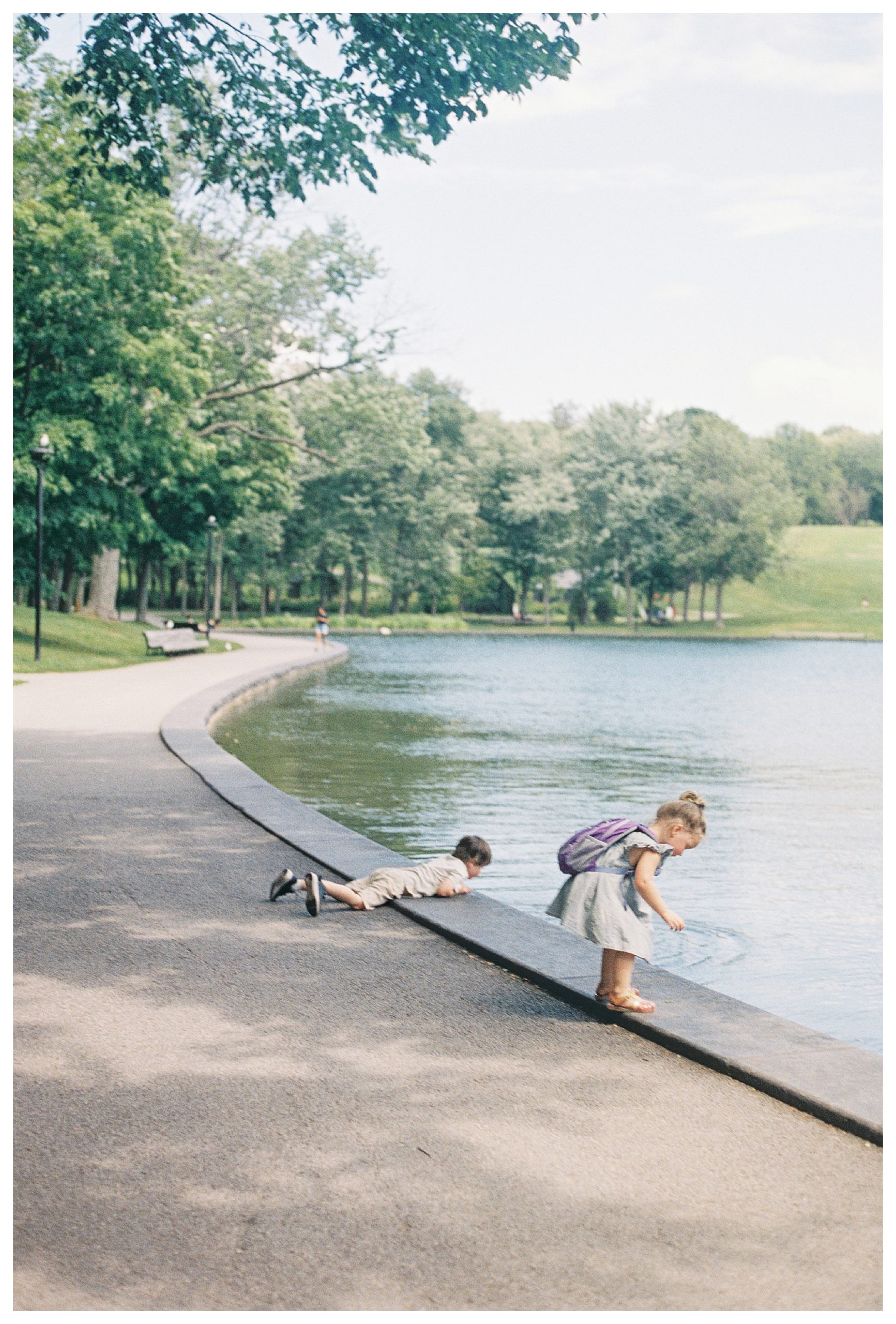 Two Young Children Lean Over A Lake In   Mont-Royal In Montreal, Canada