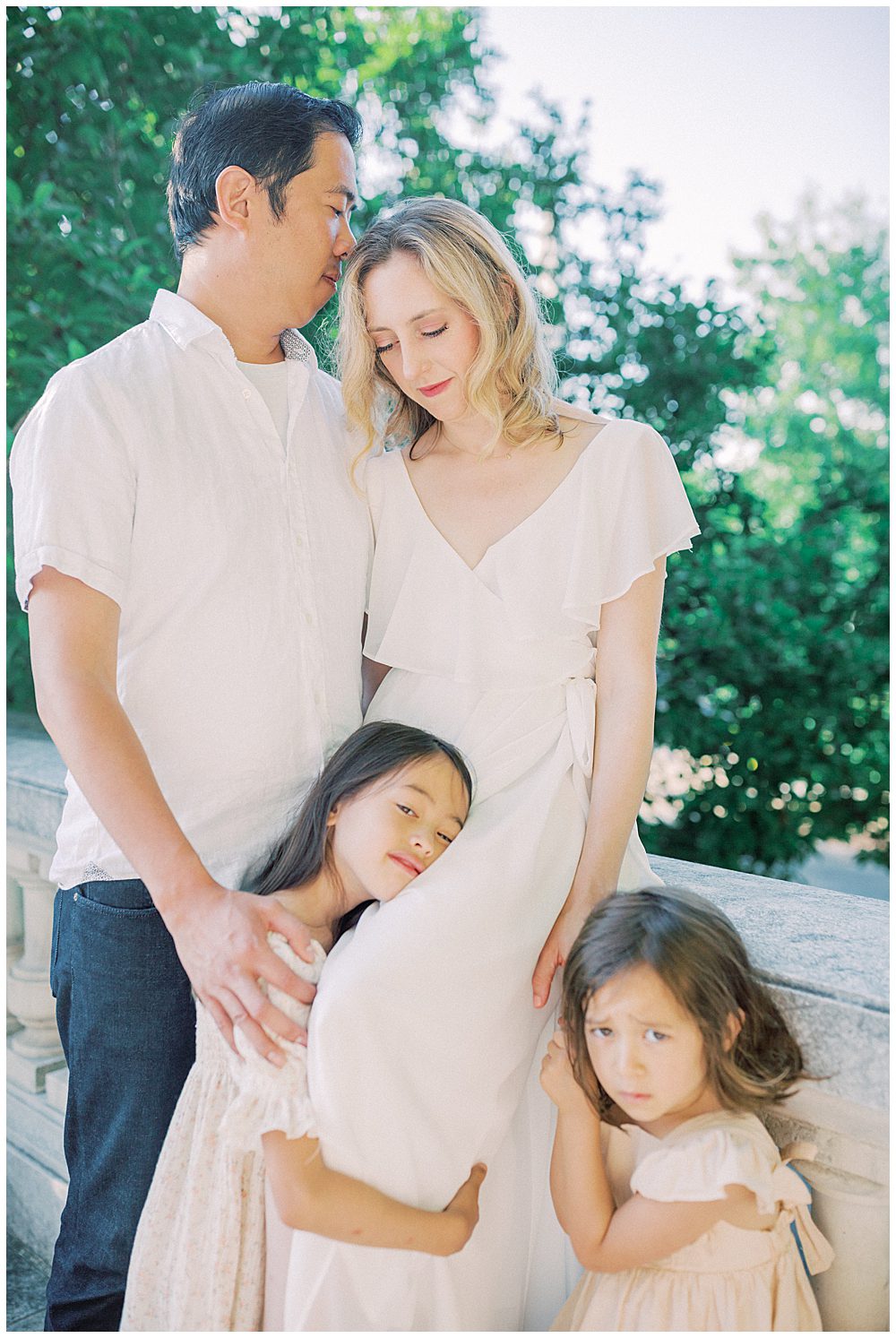 Mother, Father, And Two Girls Sit On Ledge Of Dar Constitution Hall For Family Photos.