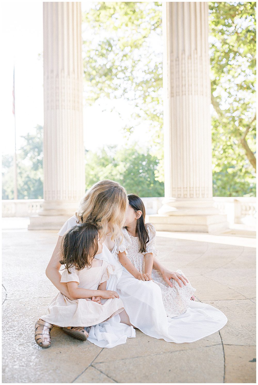 Mother Sits Under The Columns At Dar Constitution Hall With Her Two Young Daughters During Their Dar Constitution Hall Family Photo Session.