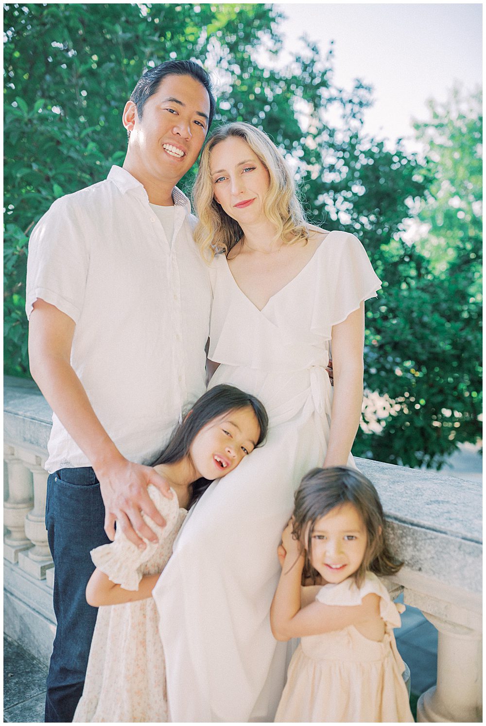 Mother, Father, And Two Young Girls Gather Close Together And Look At The Camera During Their Family Photo Session At The Dar Constitution Hall.