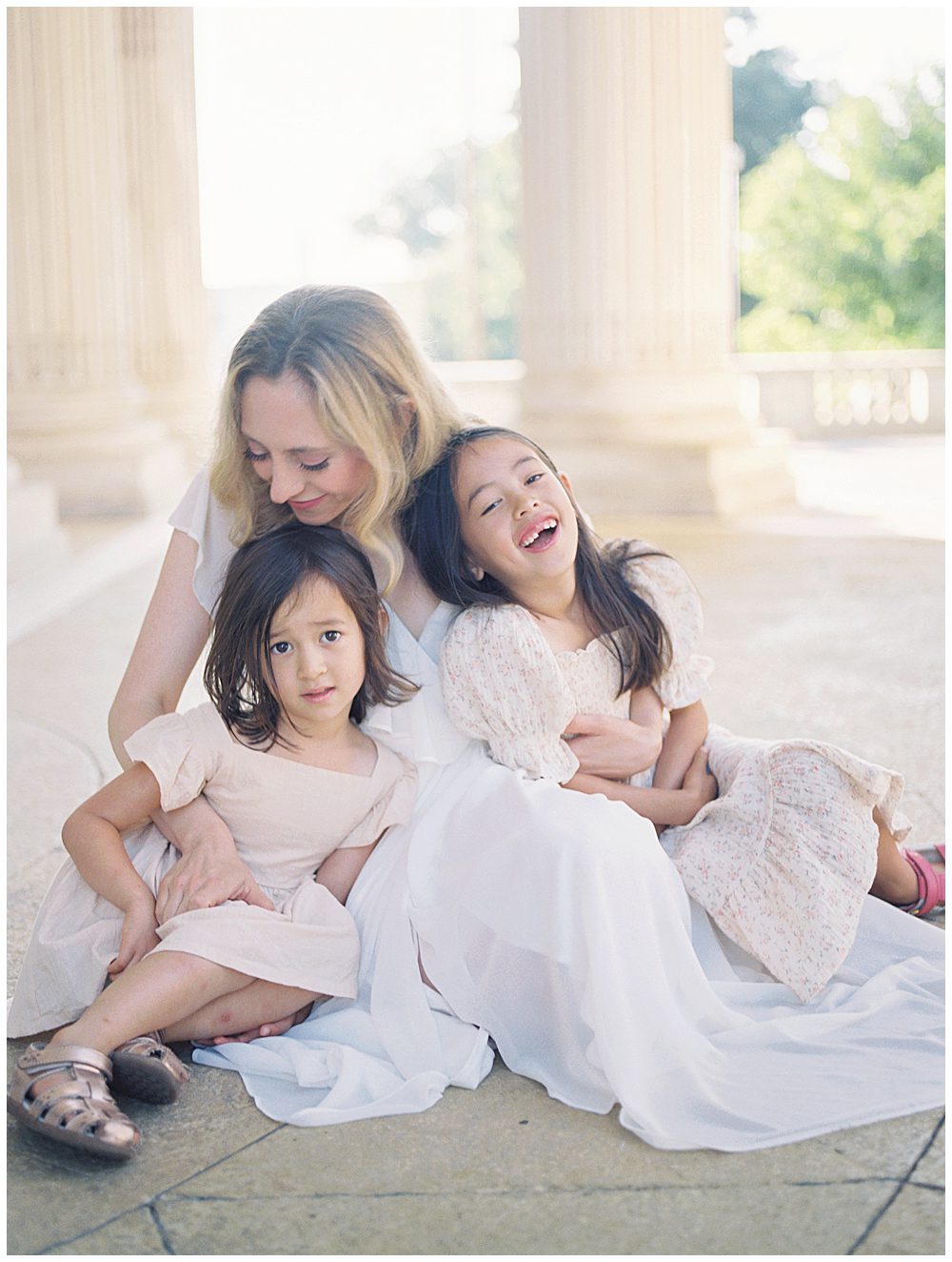 Blonde Mother Sits Underneath Columns At Dar Constitution Hall With Her Two Young Daughters Laughing.