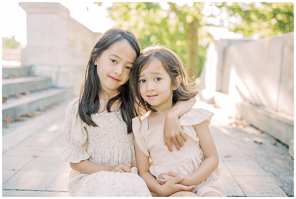 Two Sisters Sit Together On The Steps Of Dar Constitution Hall During Their Family Photo Session.