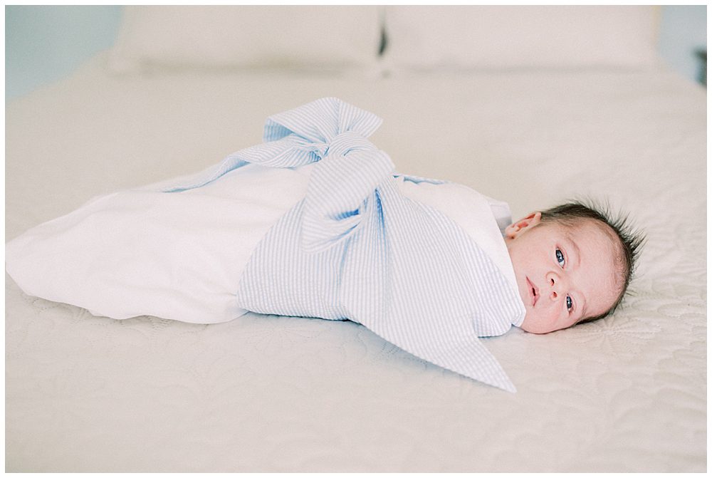 Newborn Baby Boy Wrapped In Beaufort Bonnet Company Lays On The Bed.