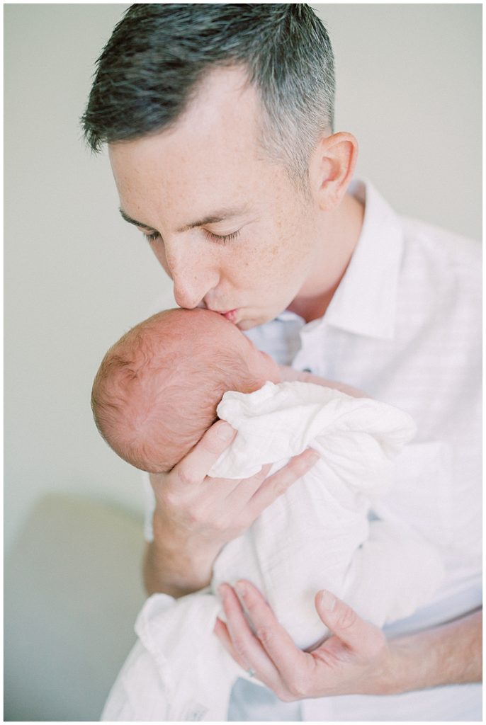 Father Brings Up His Newborn Baby For A Kiss During Their Joint Base Andrews Newborn Session.