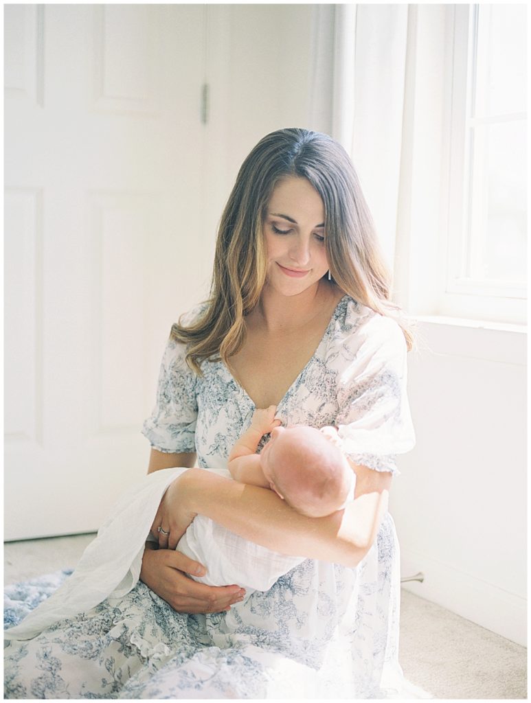 New Mother Sits In Front Of Her Window Holding Her Newborn Baby