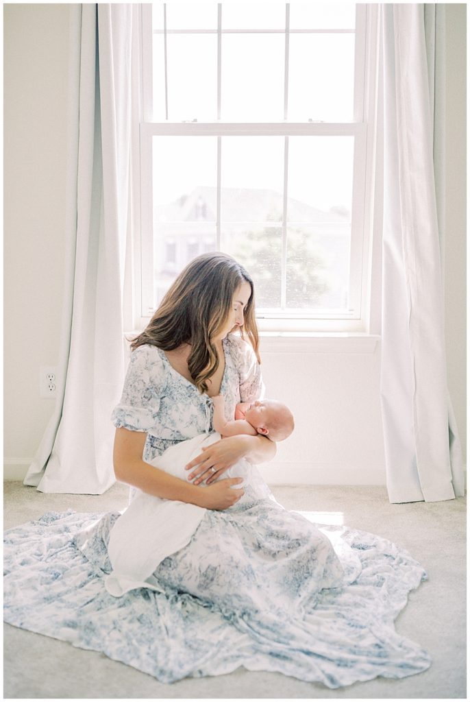 Mother Sits In Front Of The Window, Holding Her Newborn Baby Boy During Her Joint Base Andrews Newborn Session.