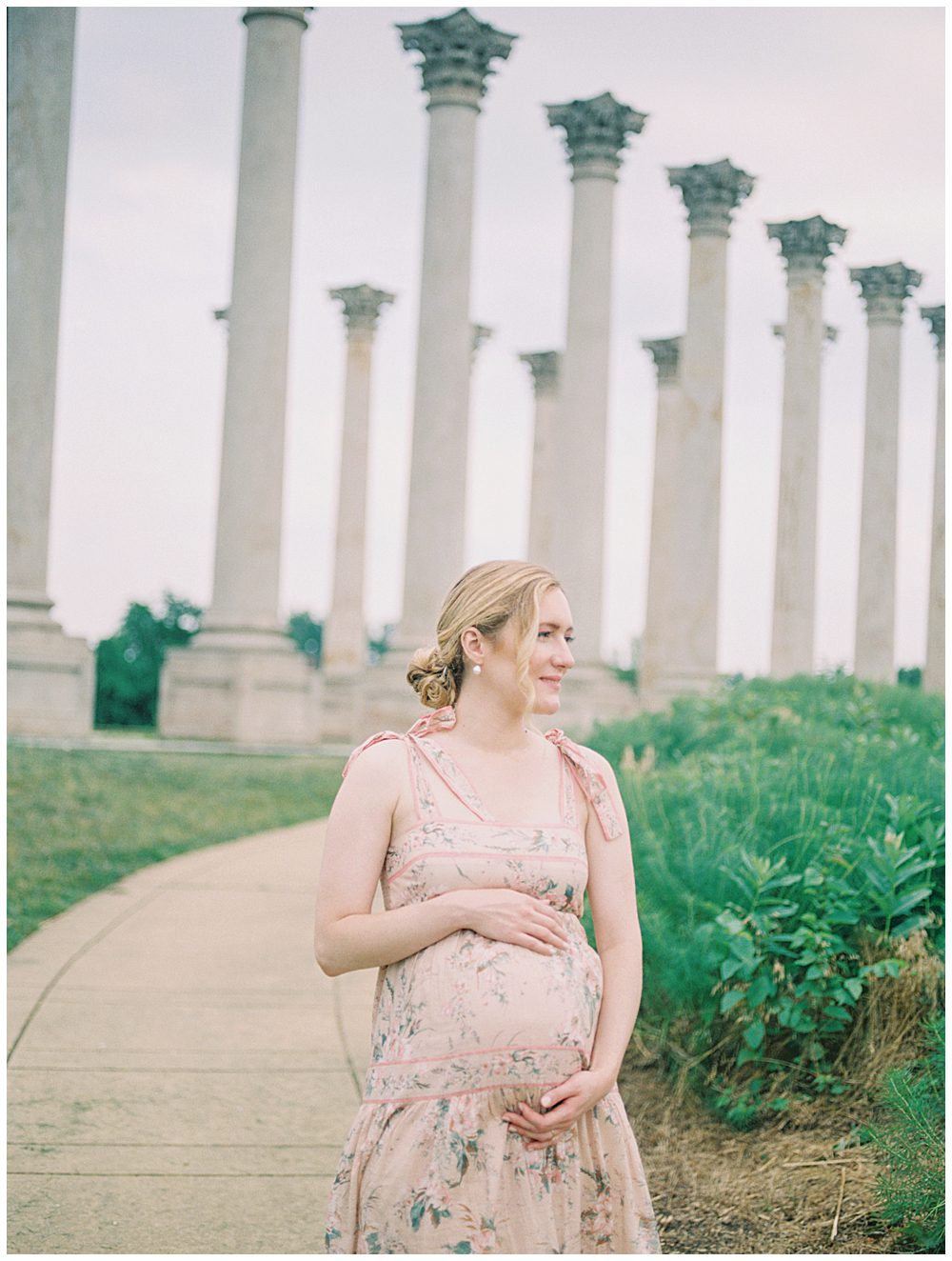 Blonde Pregnant Mother Stands In Front Of National Arboretum Columns During Her Maternity Session.