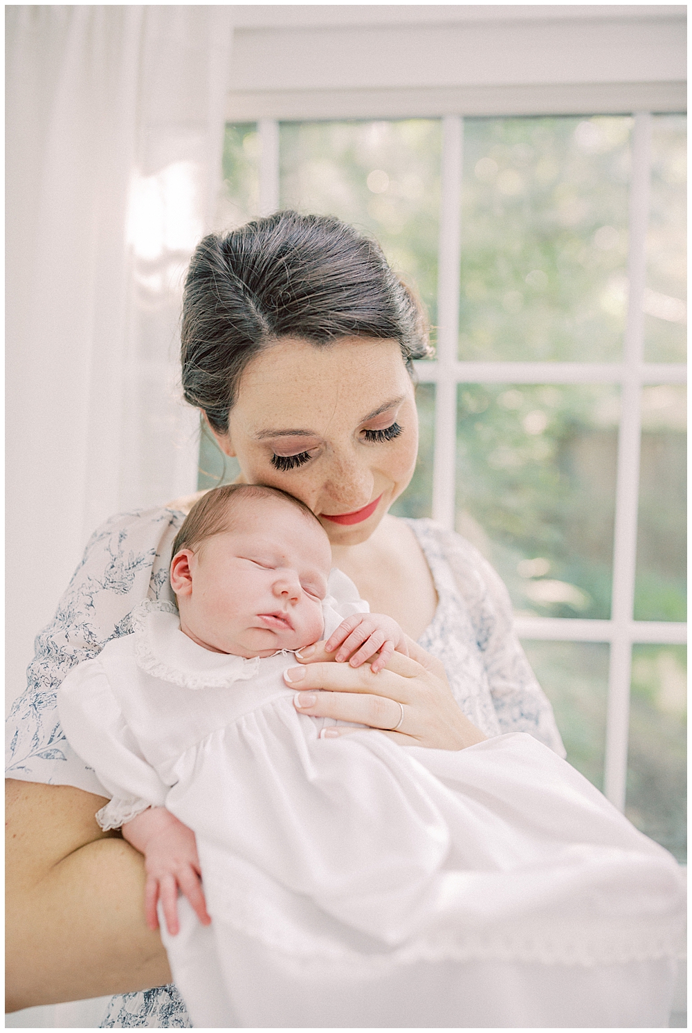 Baby Girl Held Up To Her Mother's Cheek During Her Studio Outdoor Newborn Session