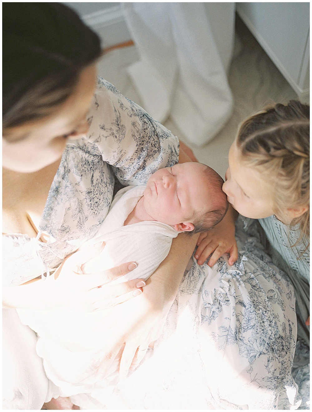 Newborn Baby Held By Her Mother Is Kissed By Her Toddler Sister