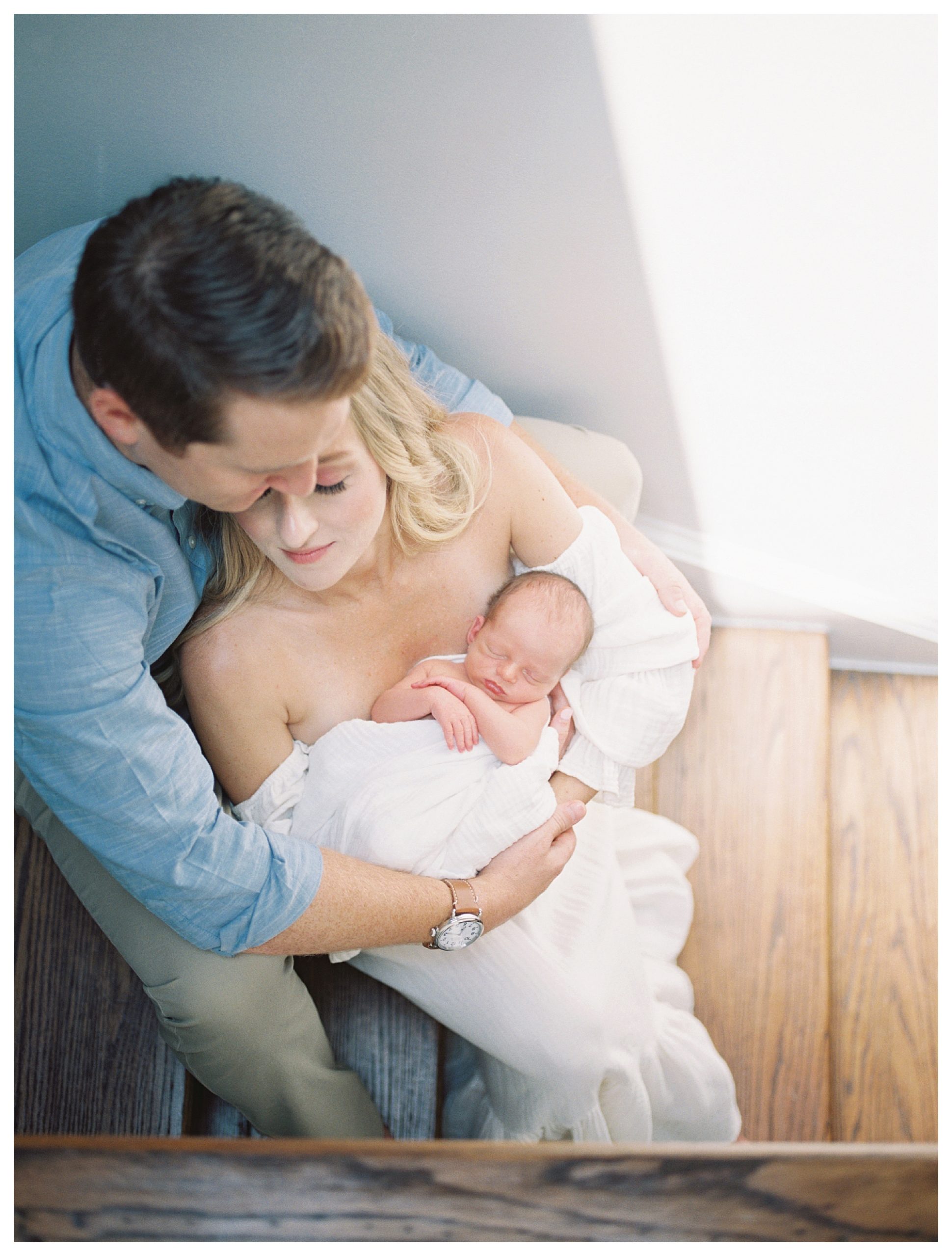 Blonde Mother Leans Into Her Husband While Holding Their Baby As They Sit On Their Steps During Their Dc Newborn Session.