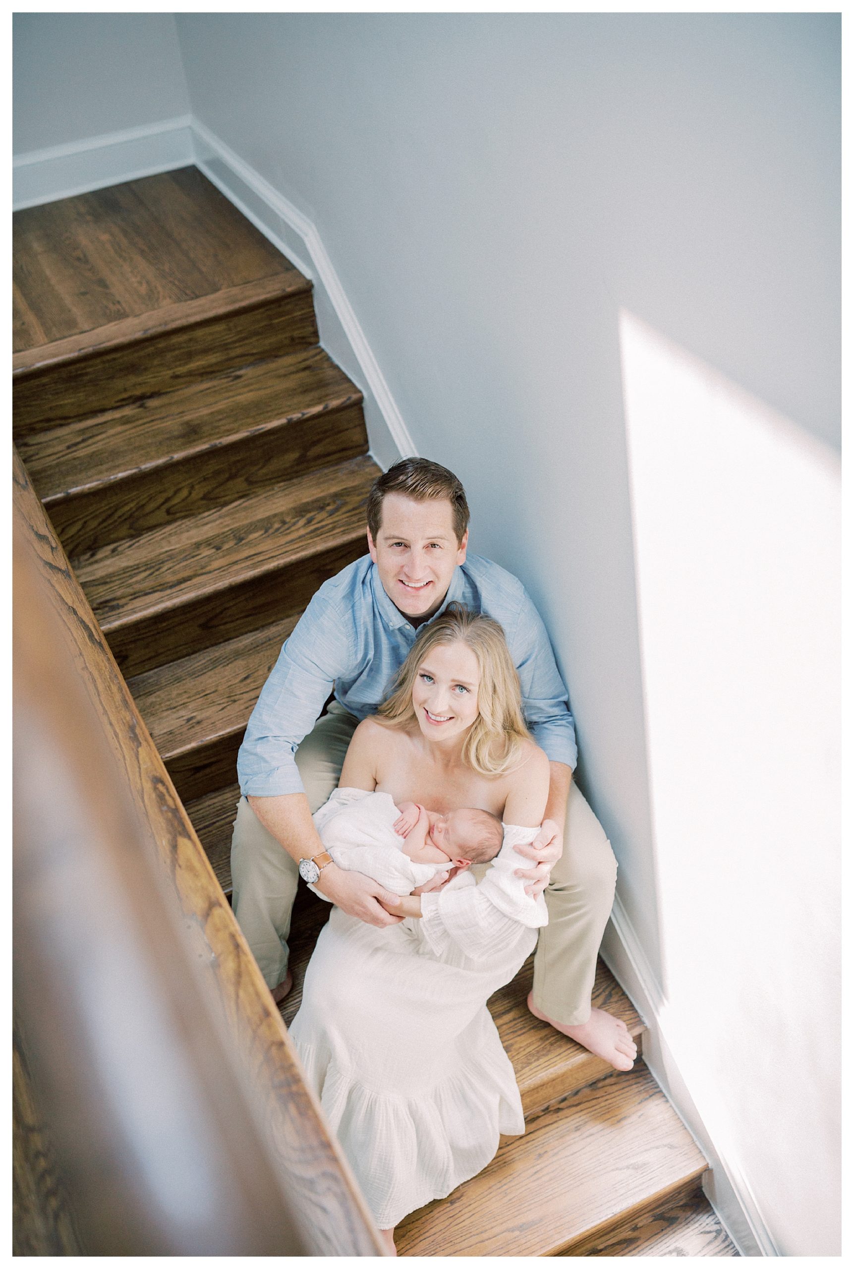 Mother And Father Sit On Steps And Smile While Holding Their Newborn Son During Capital Hill Newborn Session.