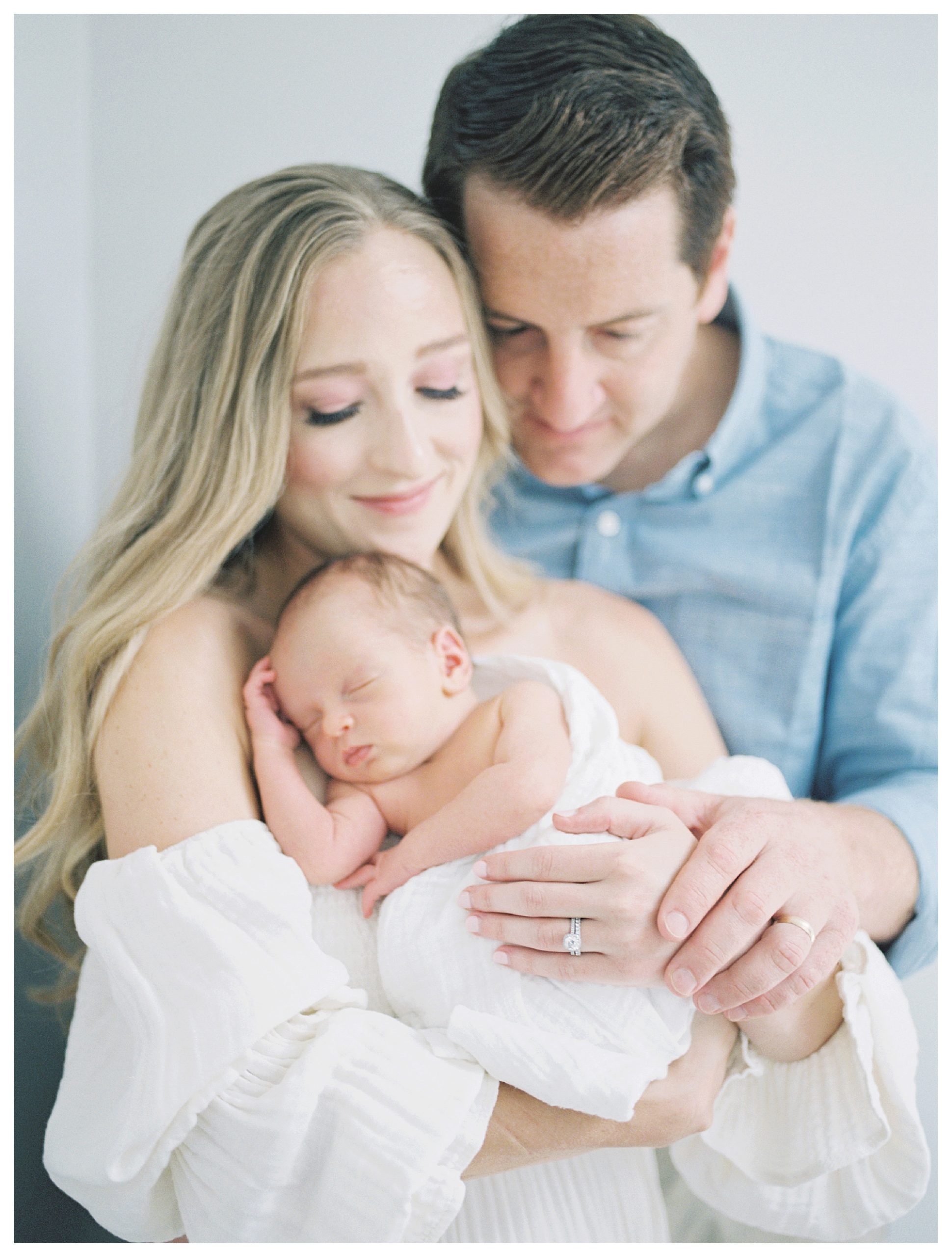 Father Leans Into His Wife Who Holds Their Newborn Son.