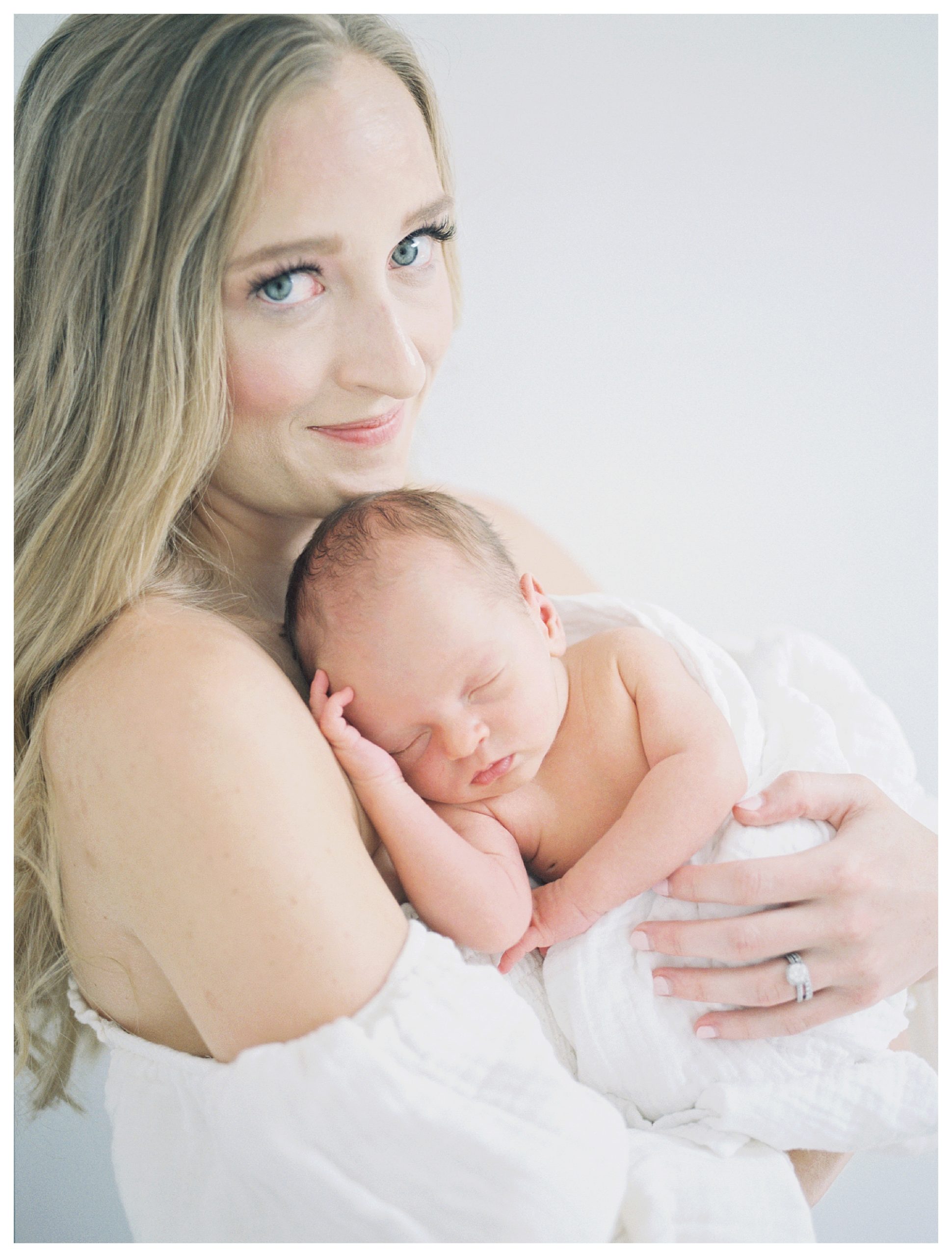 Blonde, Blue-Eyed Mother Holds Newborn Baby Up To Her Chest As She Looks At The Camera During Her Dc Newborn Session On Capital Hill.