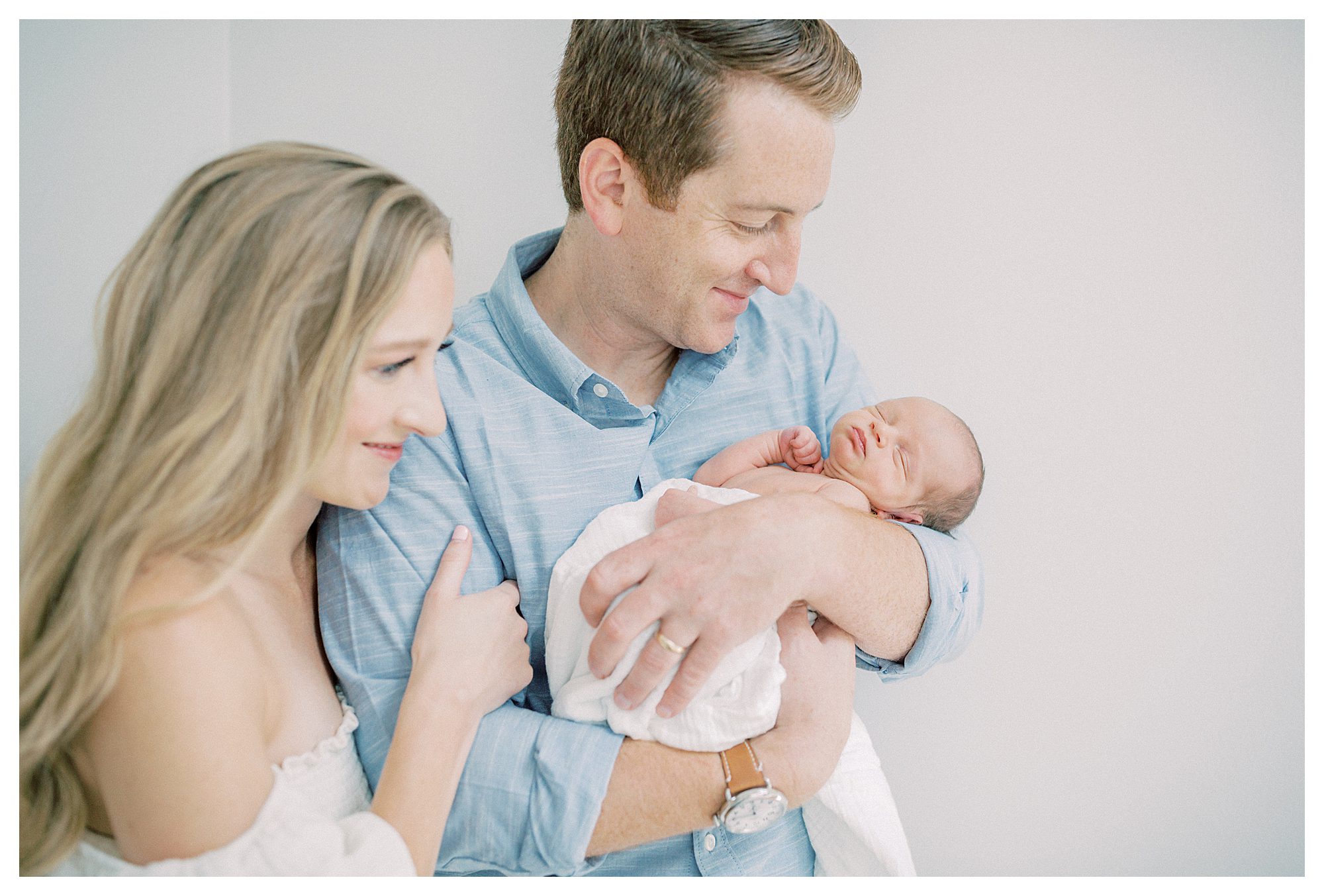 Mother And Father Smile While Admiring Their New Baby During Newborn Session On Capital Hill In Dc.