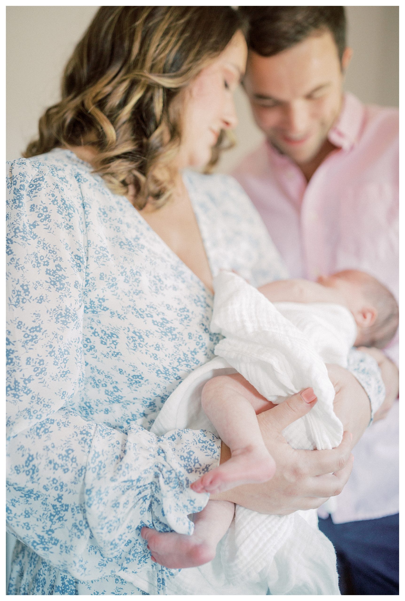 Mother And Father Hold Newborn Baby And Look Down