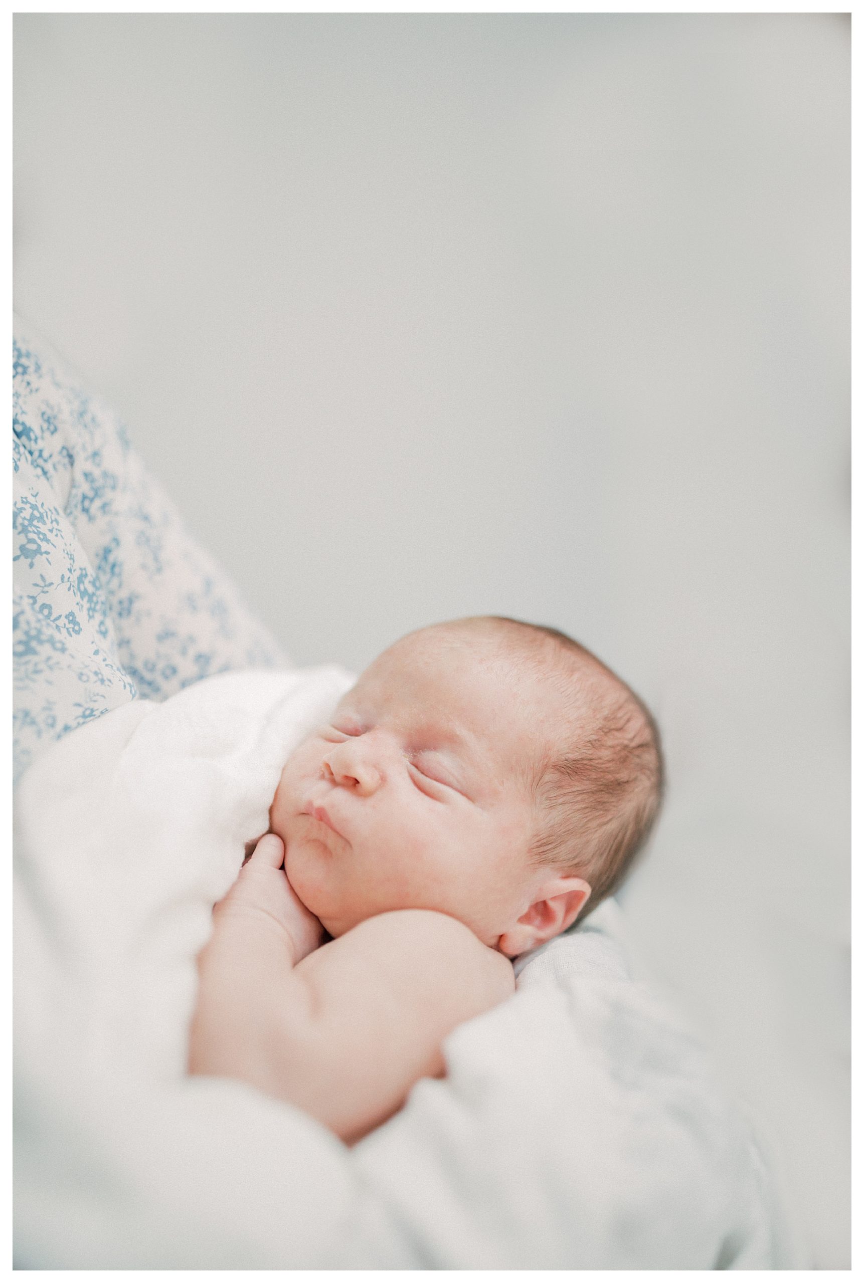 Newborn Baby Held By Parents Peacefully Sleeps.