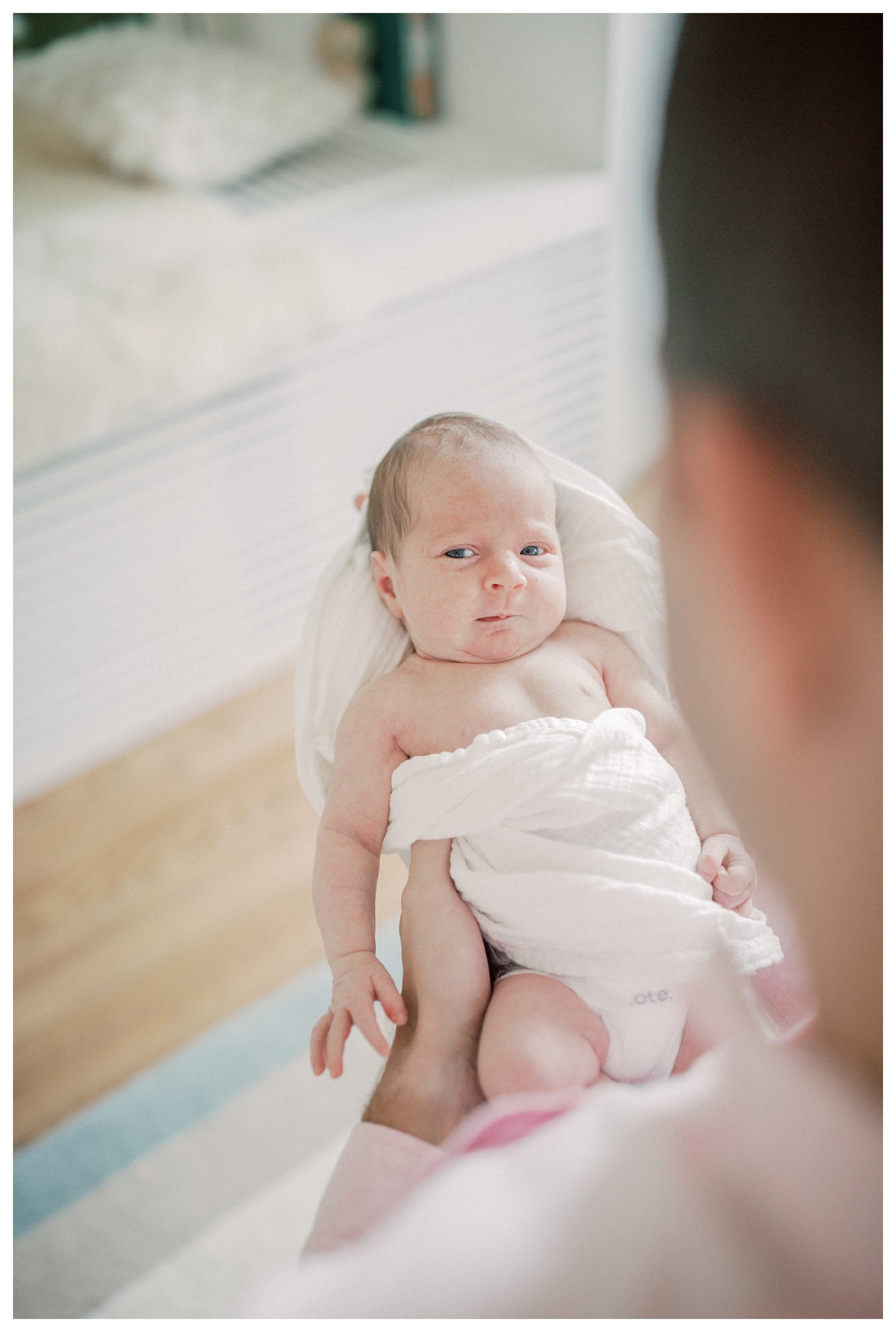 Baby Looks Up At Camera While Held By Her Father.